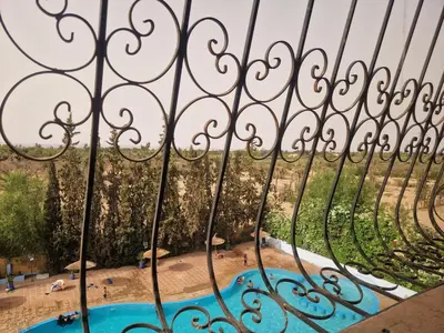 a view of a pool through a fence at Appartement 2 chambres, piscine, vue palmeraie in Marrakech