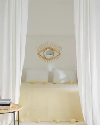 a bedroom with a bed with white curtains and an eye mirror at Riad dar Maloukti in Marrakech