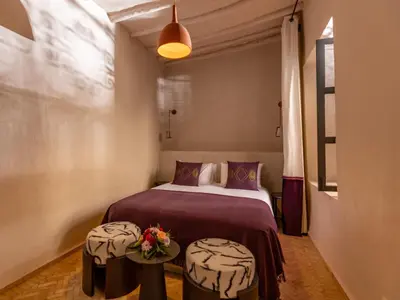 a bedroom with a bed and two tables with flowers on it at Riad Cedrat in Marrakech