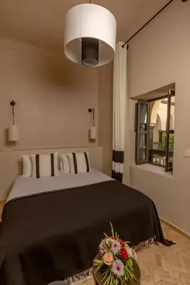 a bedroom with a bed with flowers on a table at Riad Cedrat in Marrakech