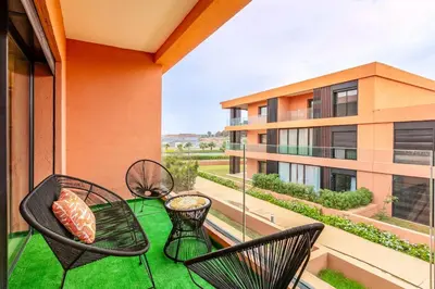 a balcony with chairs and a table and a building at Prestigia GOLF with Pool Bohemian Cocoon Stylish in Marrakech