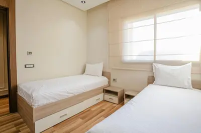 two beds in a small room with a window at Your Tiny Paradise - Marrakech - Prestigia in Marrakech