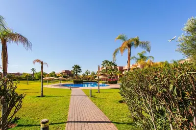a pathway in a park with palm trees and a pool at The Art of Stay - Marrakech - Prestigia in Marrakech