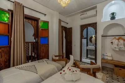 a bedroom with a bed and chairs and windows at Riad Musee in Marrakech