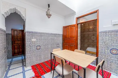 a table and chairs in a room with blue and white tiles at Dar Tbib in Marrakech