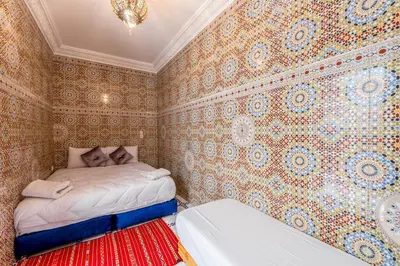 a bedroom with a bed in a room with wallpaper at Dar Tbib in Marrakech