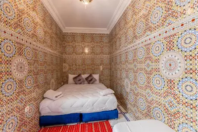 a small bedroom with a bed in a room with wallpaper at Dar Tbib in Marrakech