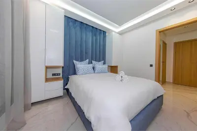 a bedroom with a large white bed with blue curtains at Chic & comfort in the heart of Marrakech train station in Marrakech