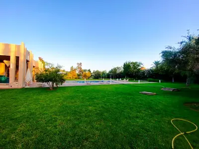 a large green yard with a building and a hose at Villa Moyen orient by séjour in Marrakech
