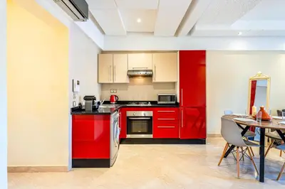 a kitchen with red cabinets and a table with chairs at Cocon de Guéliz - Central & balcon in Marrakech