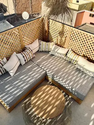 a wicker bench with pillows and a couch with aigunigunigunigun at Dar Chiba Medina in Marrakech