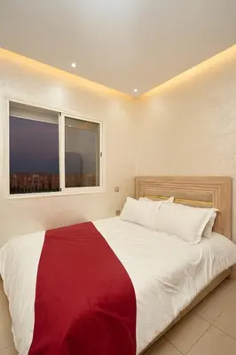 a bedroom with a large bed with a red and white blanket at Appartement l'aéroport in Marrakech
