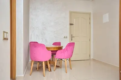 a dining room with pink chairs and a wooden table at Appartement l'aéroport in Marrakech