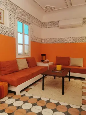 a living room with orange walls and a couch and a table at Dar Ahlam in Marrakech