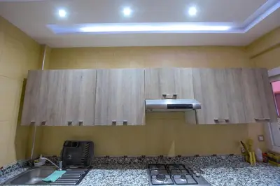 a kitchen with wooden cabinets and a sink at Appartement calme avec piscine et parking in Marrakech