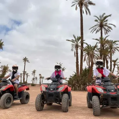 three people riding atvs on a dirt road with palm trees at Riad Zellige 95 in Marrakech