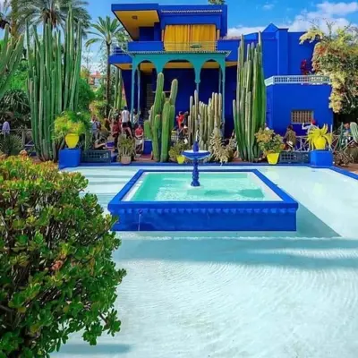 a pool with a fountain in front of a blue building at Riad Zellige 95 in Marrakech