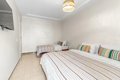 a bedroom with two beds and a flat screen tv at Massira Social Living in Marrakech