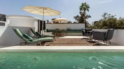 a swimming pool with chairs and a table and an umbrella at Dar 118, 3ch, hammam, piscine, rooftop, personnel in Marrakech
