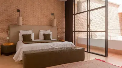 a bedroom with a large bed and a brick wall at Dar 118, 3ch, hammam, piscine, rooftop, personnel in Marrakech