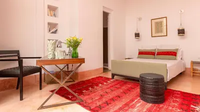 a bedroom with a bed and a table and a chair at Dar 118, 3ch, hammam, piscine, rooftop, personnel in Marrakech