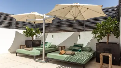 a patio with two beds and an umbrella at Dar 118, 3ch, hammam, piscine, rooftop, personnel in Marrakech