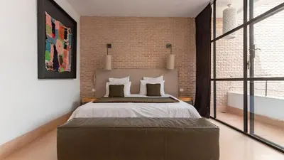 a bedroom with a large bed and a brick wall at Dar 118, 3ch, hammam, piscine, rooftop, personnel in Marrakech