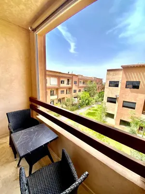 a balcony with two chairs and a table and a window at Appartement lumineux & élégant avec accès piscine in Marrakech
