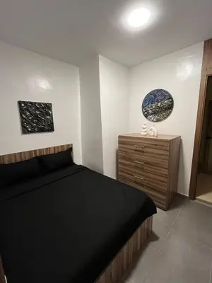 a bedroom with a black bed and a wooden dresser at Charmant appartement lumineux au cœur de la ville in Marrakech