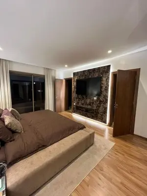 a bedroom with a large bed and a flat screen tv at Charmant appartement lumineux au cœur de la ville in Marrakech
