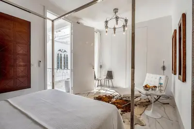 a white bedroom with a bed and a table at Riad Byerd in Marrakech