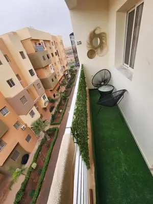 an apartment balcony with a green yard and buildings at Appartement ECHRIFIA GARDENS in Marrakech