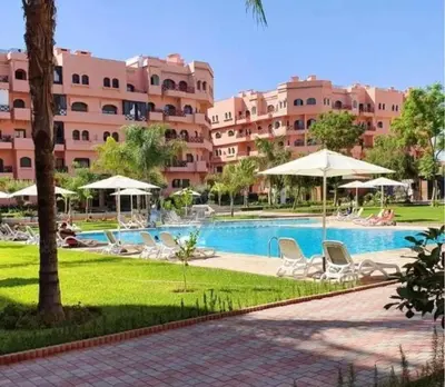 a resort with a swimming pool with chairs and umbrellas at Calme et sérénité 5 piscines Palmeraie in Marrakech