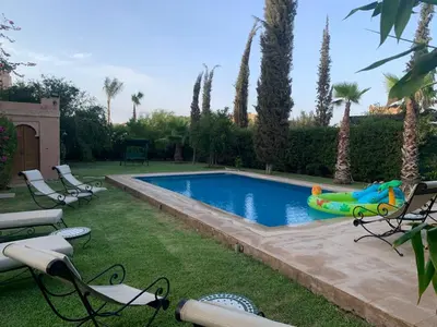 a swimming pool in a yard with chairs and a inflatable at Amour de Nuits in Douar Caïd Layadi