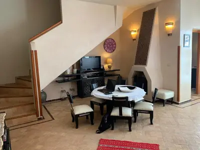 a living room with a table and chairs and a staircase at Amour de Nuits in Douar Caïd Layadi