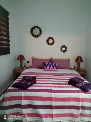 a bedroom with a large bed with a striped blanket at ATHIKA Hostel in Marrakech