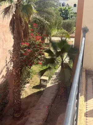 a balcony with palm trees and a bench next to a building at Cosy villa a marrakech in Marrakech