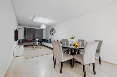 a dining room and living room with a table and chairs at 2BR Retreat in Hivernage Center with Pool, Balcony & Parking in Marrakech