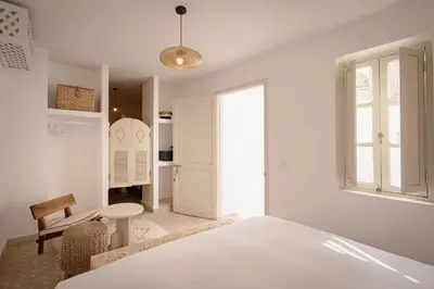 a white bedroom with a bed and a table at Riad KECH LeS ESSENTIELS in Marrakech