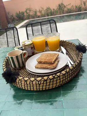 a table with a plate of toast and two glasses of orange juice at Villa Marleanis 5 suites 300m2 piscine chauffée privative 11m de long résidence avec gardien in Marrakech