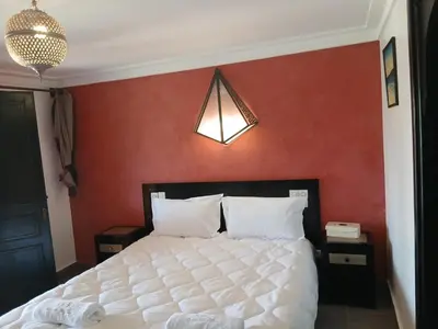 a bedroom with a white bed with a red wall at La casa de alma in Aït Hamid