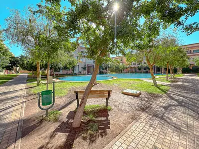 a park with a bench next to a tree at charming and cozy studio with swimming pool in Marrakech