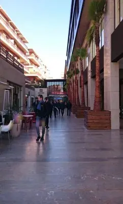 a group of people walking through a mall with palm trees at Nova Gueliz Residence in Marrakech