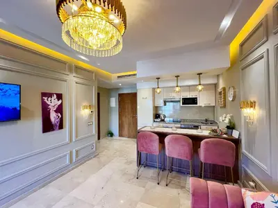 a kitchen with pink bar stools and a chandelier at Luxury Pastel Suite with Balcony & Pool in Marrakech