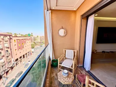 a balcony with a table and chairs and a television at Modern Gueliz Suite - Balcony Views in Marrakech