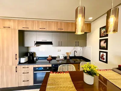 a kitchen with wooden cabinets and a wooden table at Modern Gueliz Suite - Balcony Views in Marrakech
