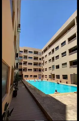 a swimming pool in front of a large building at Appart 2 chambres Gueliz in Marrakech