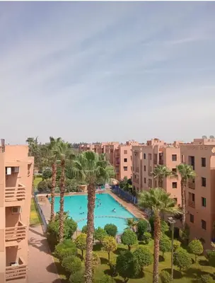 a view of a pool with palm trees and buildings at Welcome to your peaceful getaway in Marrakech! in Marrakech