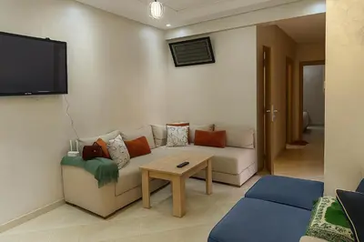 a living room with a couch and a tv on the wall at Spacious Apartment Near Menara Garden and Airport in Marrakech