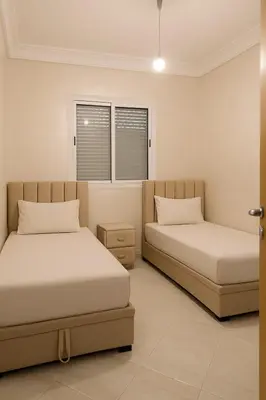 a bedroom with two beds and two windows at Spacious Apartment Near Menara Garden and Airport in Marrakech